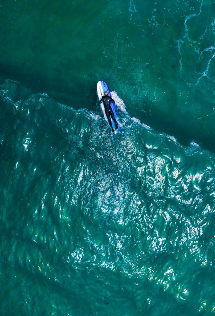 Dynamic aerial shot of a surfer on a wave showcasing the vibrant blue ocean from above.