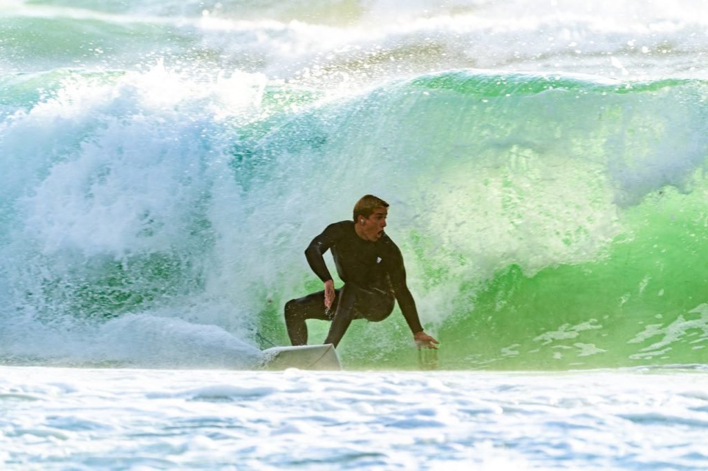 Surfer skillfully riding through a powerful ocean wave, showcasing dynamic water sports action.